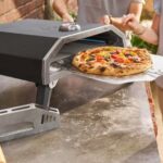Four à pizza à gaz Lidl en fonctionnement, avec une pizza qui sort du four porte ouverte