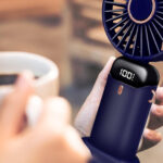 Personne en terrasse prenant un café tout en se ventilant avec un mini ventilateur portable