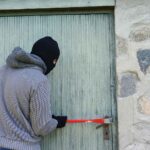Personne tentant de forcer une porte d’entrée avec un pied de biche