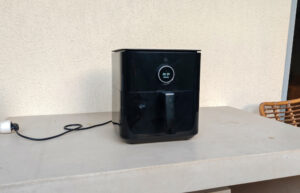 Airfryer posé sur un balcon, branché à une rallonge électrique extérieure