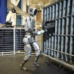 Robot Atlas de Boston Dynamics interagissant avec une armoire dans une usine, montrant sa précision et son agilité.