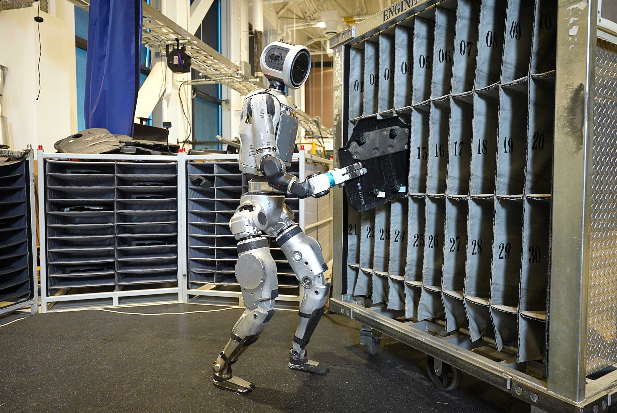 Robot Atlas de Boston Dynamics interagissant avec une armoire dans une usine, montrant sa précision et son agilité.
